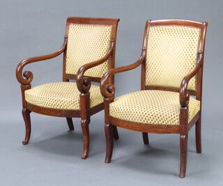 A matched pair of Empire style mahogany open armchairs, the seats and backs upholstered in gold material, raised on outswept supports 