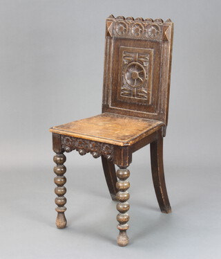 A Victorian carved oak hall chair with solid seat and back, raised on bobbin turned supports
