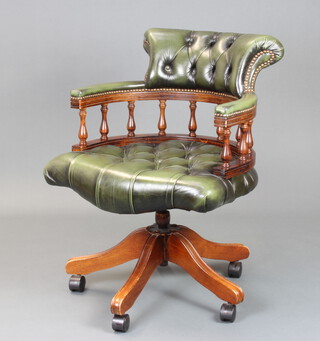A Victorian style mahogany revolving office chair upholstered in green buttoned leather, raised on a tripod base 