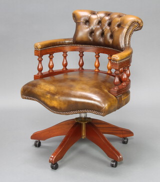 A Victorian style mahogany swivel tub back office chair upholstered in brown buttoned back leather 