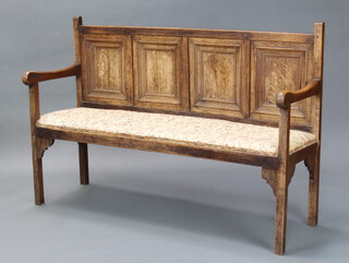 A bleached oak settle of panelled construction, having an upholstered seat and raised on square supports 92cm h x 139cm w x 45cm d 