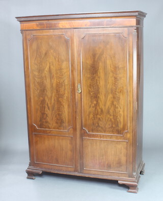 Waring and Gillows, a 19th Century mahogany wardrobe with moulded and dentil cornice, enclosed by panelled doors with fluted canted corners, raised on ogee bracket feet 183cm h x 132cm w x 57cm d 