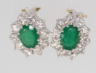 A pair of 18ct yellow gold oval emerald and diamond cluster earrings, the emeralds 3.6ct, the brilliant cut diamonds 3ct 