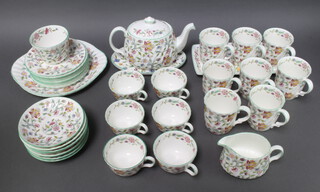 A 37 piece Minton Haddon Hall tea service comprising teapot, cream jug (second) sugar bowl (second), rectangular plate (second), oval dish, 2 circular twin handled plates (seconds), 8 tea plates, 8 saucers, 6 tea cups (5 seconds and 1 chipped), 8 mugs (all seconds)