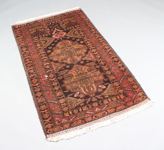 A red and black ground Belouche rug with 2 stylised medallions to the centre 142cm x 90cm 