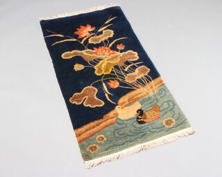 A 1930's blue ground Chinese rug decorated a river, ducks and plants 121cm x 64cm 