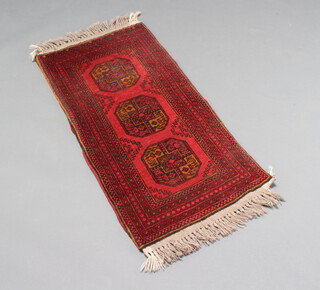 A black and red ground Afghan rug with 3 diamonds to the centre 113cm x 152cm 
