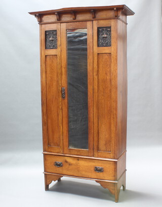 An Edwardian Art Nouveau light oak wardrobe with shaped cornice fitted a mirrored panelled door, base fitted a drawer, raised on square supports 186cm h x 106cm w x 54cm d 