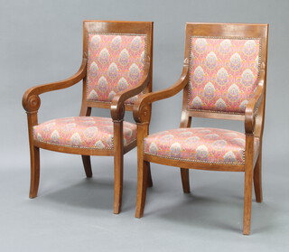 A pair of mahogany Empire style open arm chairs upholstered in floral material, raised on outswept supports 