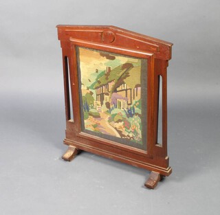 A 1930's oak fire screen with Berlin woolwork panel of a cottage 67cm h x 56cm w x 18cm d 