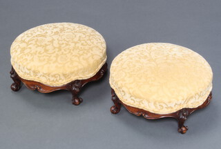 A pair of Victorian circular carved walnut show frame footstools, the seats upholstered in yellow sculptured material raised on cabriole supports 14cm x 34cm 