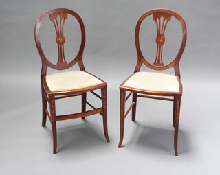 A pair of Edwardian Sheraton Revival painted mahogany bedroom chairs with vase shaped splat backs and upholstered seats, raised on outswept supports 