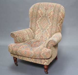 A Victorian style armchair upholstered in tapestry material, raised on turned supports 
