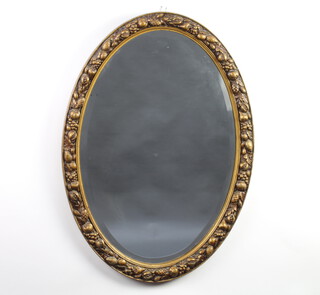 A 1930's oval bevelled plate wall mirror contained in a decorative gilt frame with fruit decoration 75cm x 42cm 