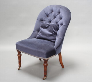 An Early Victorian nursing chair upholstered in blue buttoned material, raised on turned and fluted supports 