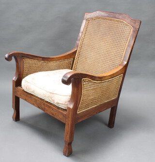 A hardwood double cane bergere armchair, raised on shaped supports 