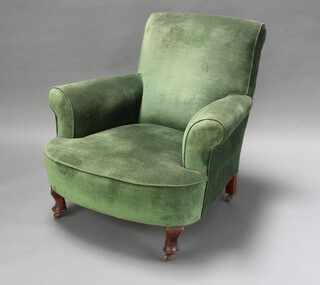 A Howard style armchair upholstered in green material and raised on cabriole supports with metal casters 