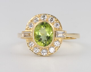 An 18ct yellow gold peridot and diamond cluster ring, the centre oval stone approx. 1.3ct surrounded by brilliant and baguette cut diamonds 0.5ct, size N 1/2