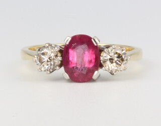 An 18ct yellow gold ruby and diamond ring, the centre oval stone approx. 1.5ct, flanked by 2 brilliant cut diamonds approx. 0.8ct, size R 1/2