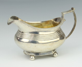 A George IV silver milk jug raised on ball feet with chased monogram, London 1825, 198 grams
