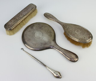 A hammered pattern silver hand mirror Chester 1917, a similar hairbrush, clothes brush and button hook, mixed dates 