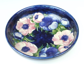 A William Moorcroft shallow bowl the blue ground decorated the anemone design, impressed signature marks and paper label to the base, 27cm 