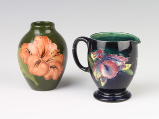 A William Moorcroft blue ground jug decorated with the orchid design, base with impressed signature marks, 7cm, together with a Moorcroft baluster vase the green ground decorated the hibiscus patern, 9cm 