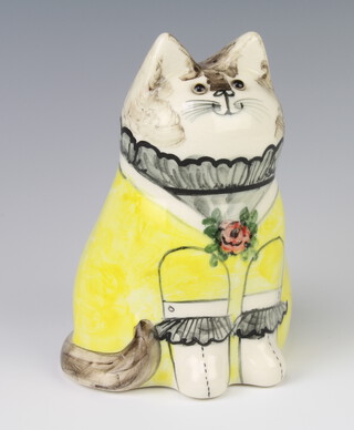 A Rye Pottery seated cat by Bethel dated 1988, with glass eyes, wearing a yellow dress 19cm 