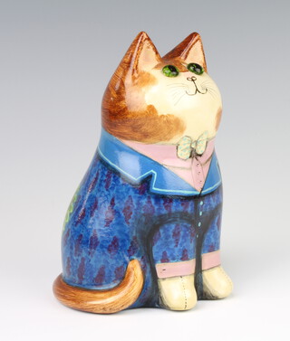 A Rye Pottery cat by Joan and David De Bethel, with glass eyes, dated 1982, wearing a frock coat with rose in his lapel, inscribed Never stop to question why do a good deed passing by, 17cm 