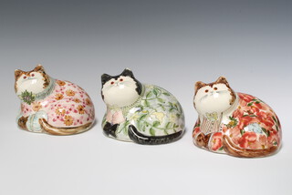 Three Rye Pottery figures of reclining cats, 2 dressed in suits with floral decoration and a feline cat decorated flowers, all with glass eyes 11cm 