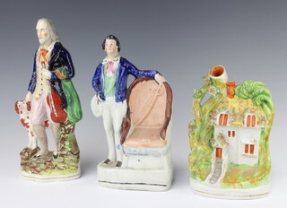 A Victorian Staffordshire figure of a gentleman standing beside a chair 25cm, a ditto of a man holding a violin with spaniel 28cm and a spill vase in the form of a cottage 20cm 