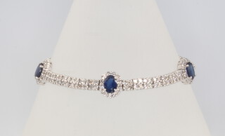 An 18ct white gold sapphire and diamond cluster bracelet, diamonds 5ct, sapphires 5ct, 18cm 