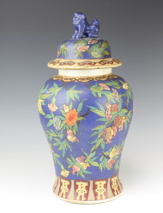 An 18th Century style Chinese baluster vase and cover, the blue ground decorated with flowers, having a shi shi finial 47cm 