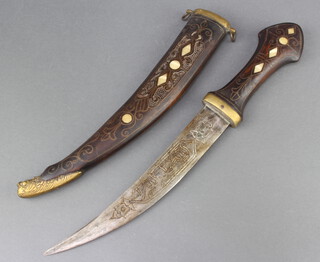 An Eastern dagger with 23cm engraved blade contained in an hardwood and mother of pearl scabbard 