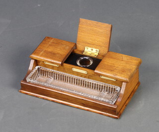 An Edwardian oak 3 division ink stand with hinged lid revealing 3 associated inkwells and having a glass pen tray 8cm h x 27cm w x 14cm d  