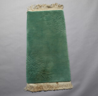 A sculpted green ground Chinese rug with blue decoration 129cm x 64cm 