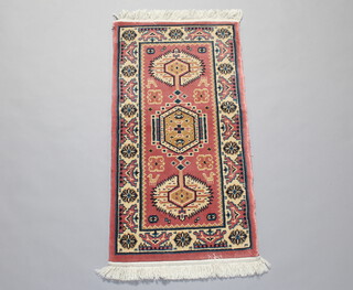 A pink and white ground Persian style machine made rug with geometric designs 122cm x 61cm 