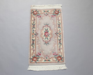 A beige floral patterned Chinese rug 130cm x 68cm 