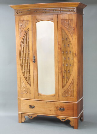 An Edwardian Art Nouveau carved and pierced satinwood wardrobe with moulded cornice, fitted a cupboard enclosed by arched mirrored panelled door, base fitted a drawer 199cm h x 104cm w x 43cm d 