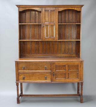An Edwardian Art Nouveau oak dresser, the raised back with moulded cornice fitted a cupboard enclosed by a panelled door, flanked by 2 shelves above a recess, the base fitted 3 long drawers flanked by a cupboard enclosed by panelled doors, raised on turned and block supports with H framed stretcher 198cm h x 136cm w x 49cm d 