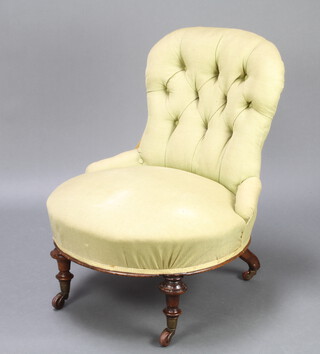 A Victorian nursing chair upholstered in green buttoned material raised on turned and fluted supports 