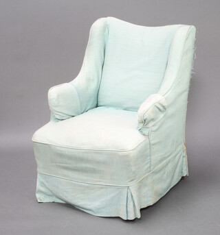 An Edwardian winged armchair with blue loose cover, raised on turned supports 