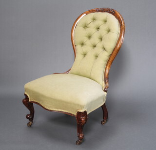 A Victorian carved mahogany show frame nursing chair upholstered in green buttoned material, raised on cabriole supports