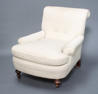 A Howard style armchair upholstered in white material, raised on turned supports