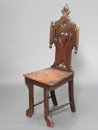 A Continental carved oak hall chair with pierced and carved back, solid seat, raised on outswept supports with turned stretchers