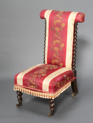 A Victorian prie dieu chair upholstered in pink and red floral material with spiral turned columns to the side, raised on turned supports with brass caps and casters