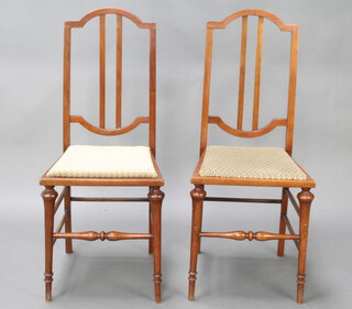 A pair of Edwardian mahogany stick and rail back bedroom chairs with upholstered seats, raised on turned supports