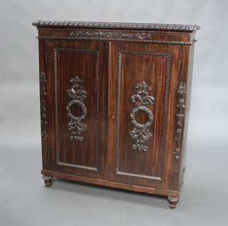 A 19th Century Indian carved "pine and coromandel" cabinet, fitted shelves enclosed by panelled doors, raised on bun feet 125cm h x 109cm w x 48cm d 
