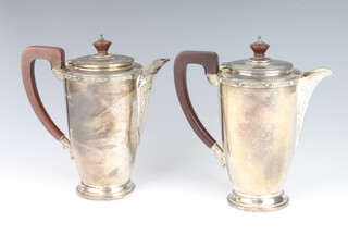 A pair of silver coffee and milk jugs with Arts and Crafts decoration, fruit wood handles, Birmingham 1959, maker Adie Brothers, 966 grams gross 