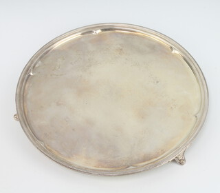 A circular silver salver with beaded rim and engraved monogram on scroll feet, Sheffield 1928, Roberts & Belk, 340 grams, 25cm 